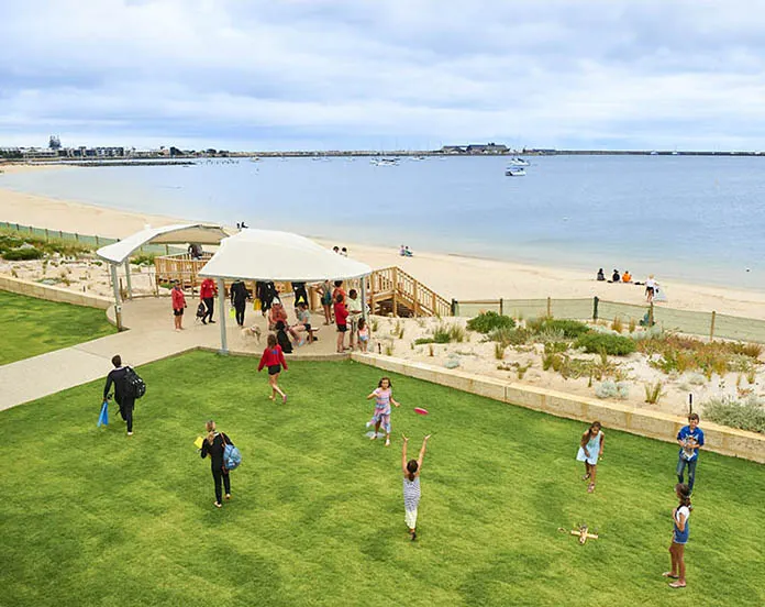 People on a grassy foreshore beside a beach